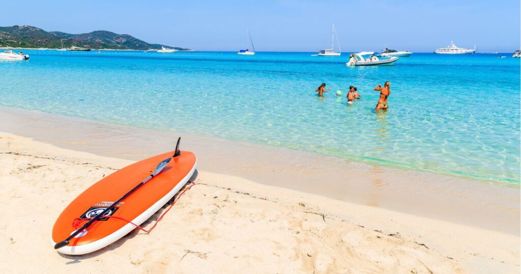 madre che cattura maschera dei suoi bambini che giocano in acqua sulla spiaggia idilliaca di Saleccia